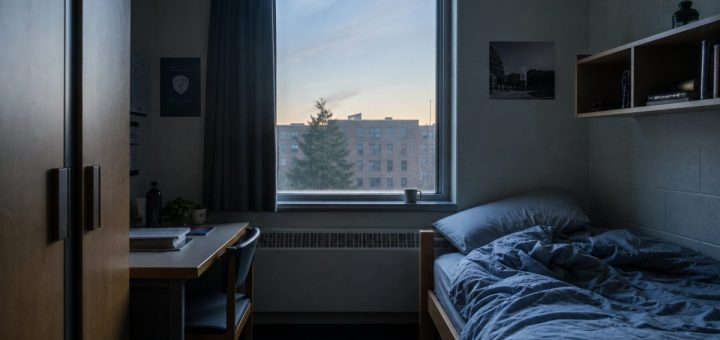 An empty student dormitory room at dawn, soft blue-grey light coming through a half-drawn curtain, an unmade bed with rumpled sheets, a ceramic cup left on the windowsill, still and quiet atmosphere, interior architectural photography. Use balanced, natural contrast with a realistic tonal range. Preserve fine detail throughout the image, with smooth highlight roll-off, detailed shadows, balanced exposure, and natural, accurate colors.